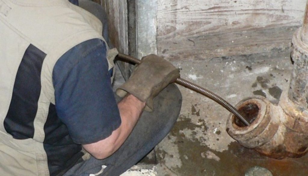 a plumber snaking a drain pipe
